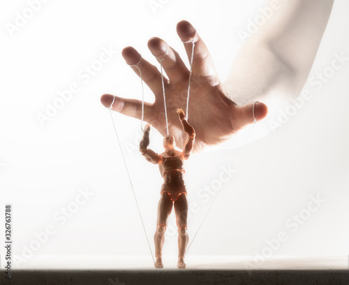 Photography Concept of control. Marionette in human hand. Image on white.
