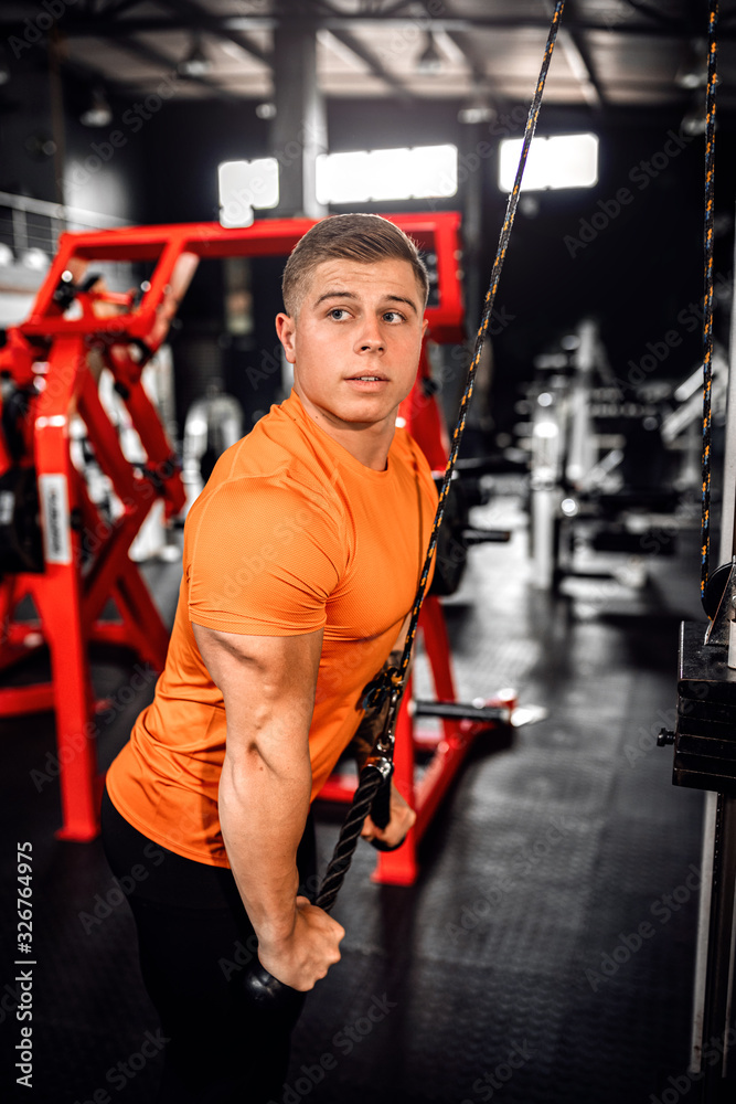 © JonoErasmus - Fit young man doing cable tricep pulldowns during a workout