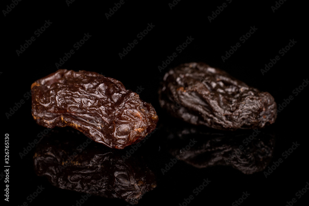 Group of two whole dried dark raisin isolated on black glass Group of two whole dried dark raisin isolated on black glass