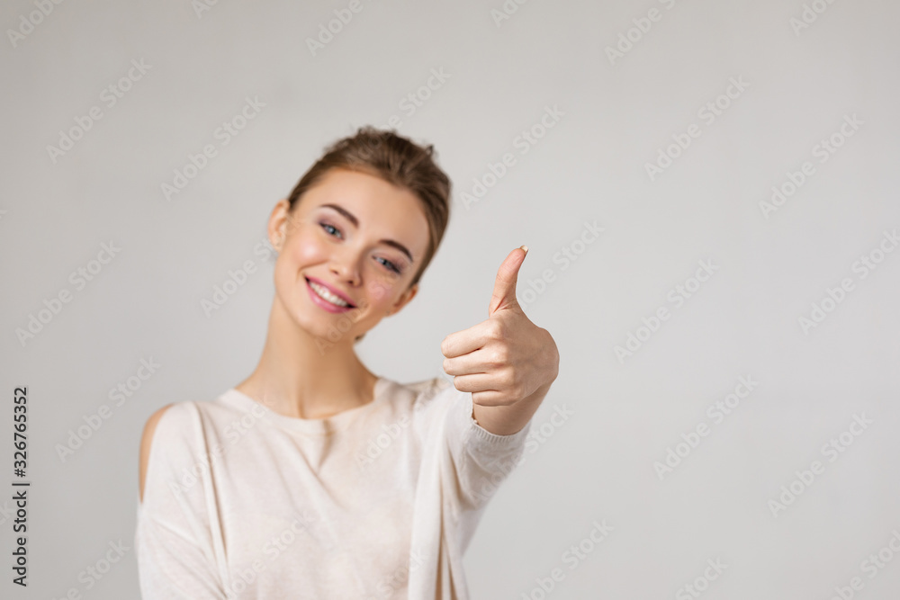 Portrait of young beautiful caucasian woman showing thumbs up on gray background Portrait of young beautiful caucasian woman showing thumbs up on gray background