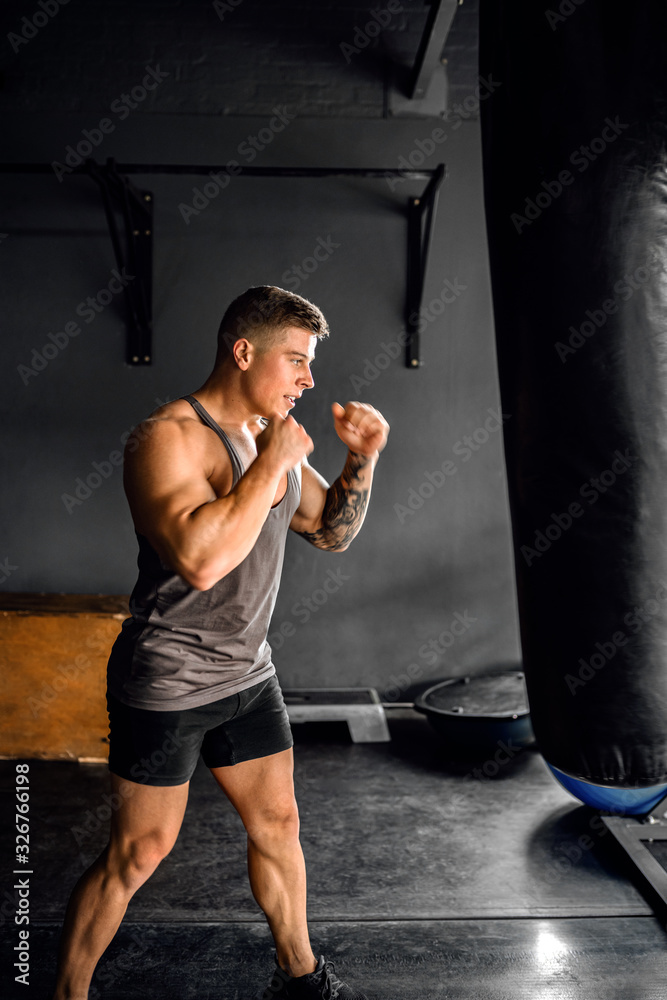 Fit young man working out on a gym heavy bag