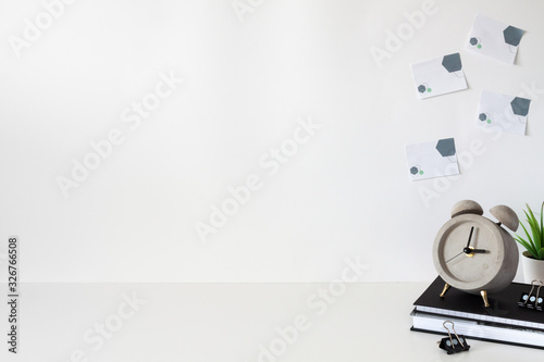 School desk against an empty white wall. Copy space. Books, succulent and alarm clock. Sticky notes. photo