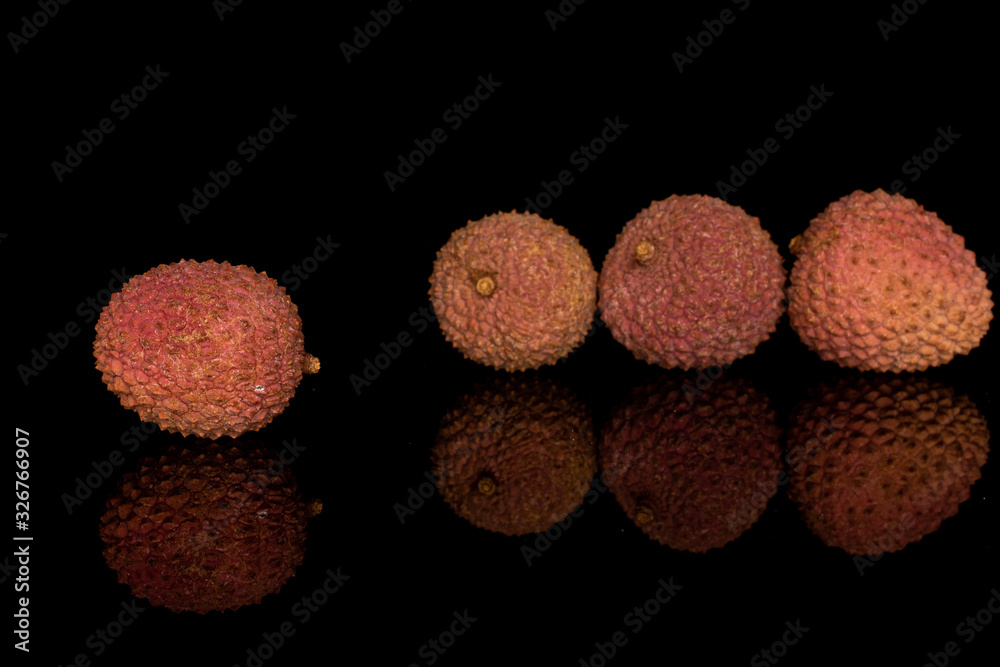 Group of four whole fresh lychee isolated on black glass Group of four whole fresh lychee isolated on black glass