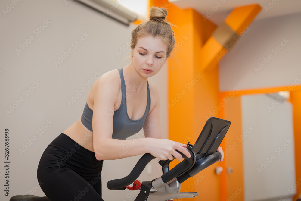 Woman doing cardio workout biking training in indoors gym Woman doing cardio workout biking training in indoors gym
