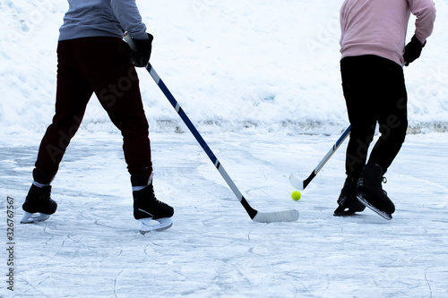 Canvas Print A young guys play amateur ice hockey with hockey sticks and ball