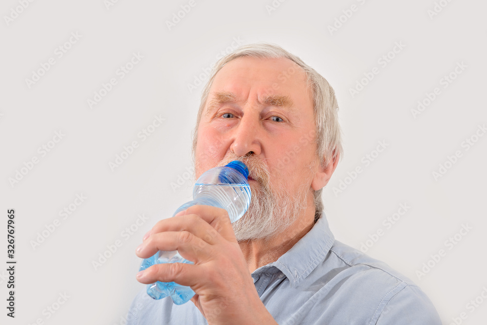 Senior man is drink water from bottle. Pensioner with gray hair and beard. Senior man is drink water from bottle. Pensioner with gray hair and beard.
