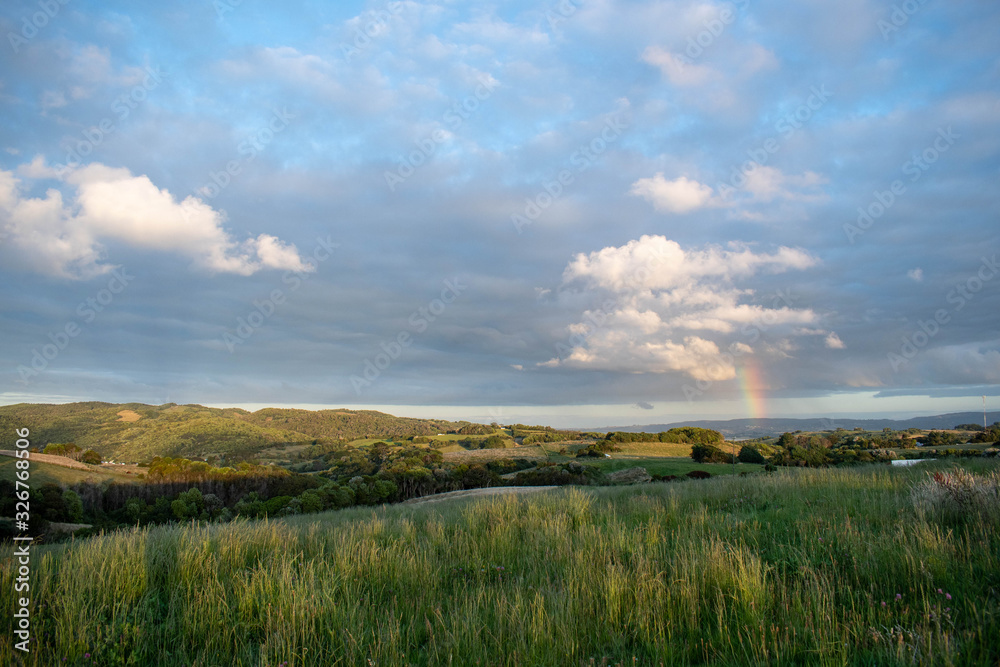A rainbow on a cloudy day and green meadow at Chiloe Island A rainbow on a cloudy day and green meadow at Chiloe Island