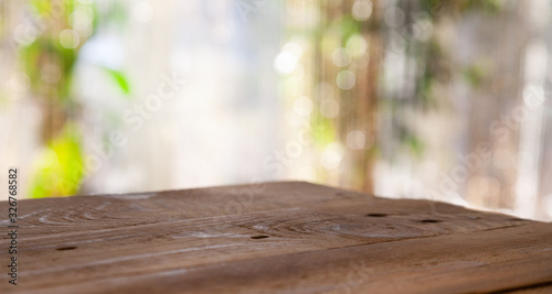 Top of wooden table on window glass blur. Of green from the garden of the vegetable garden on a morning background. To display product montage.