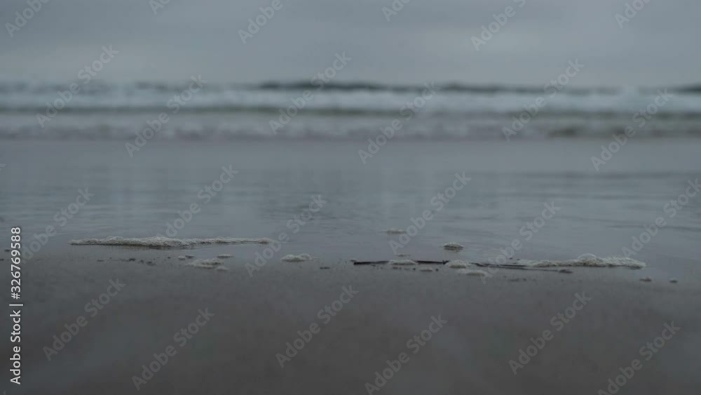 Closeup of sandy beach with waves in background Closeup of sandy beach with waves in background