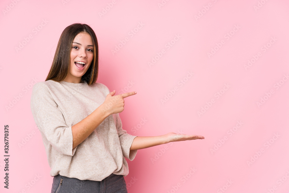 Young caucasian woman posing isolated excited holding a copy space on palm. Young caucasian woman posing isolated excited holding a copy space on palm.