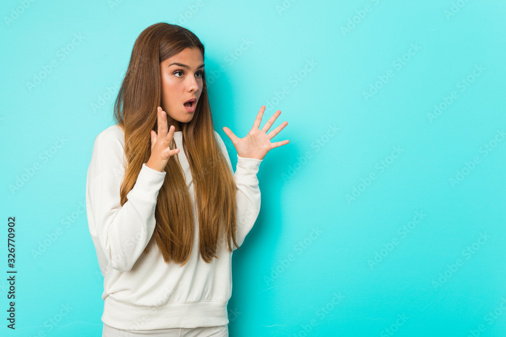 Fototapeta premium Young slim woman shouts loud, keeps eyes opened and hands tense.