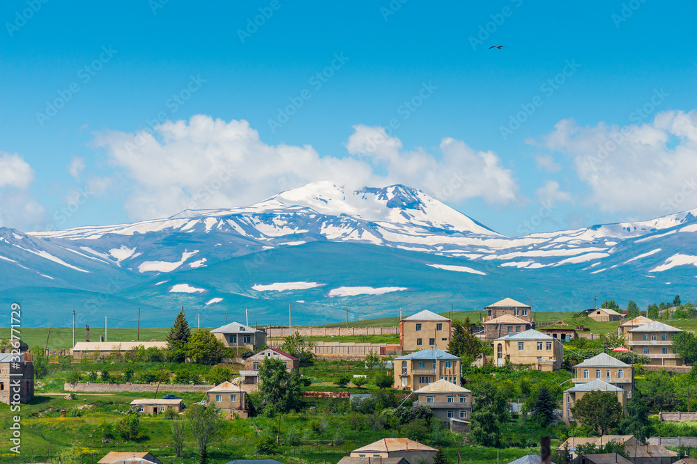 Armenian mountain with a snowy peak and a view of the Armenian village
