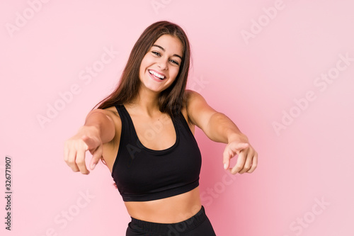 Young caucasian fitness woman doing sport isolated cheerful smiles pointing to front.
