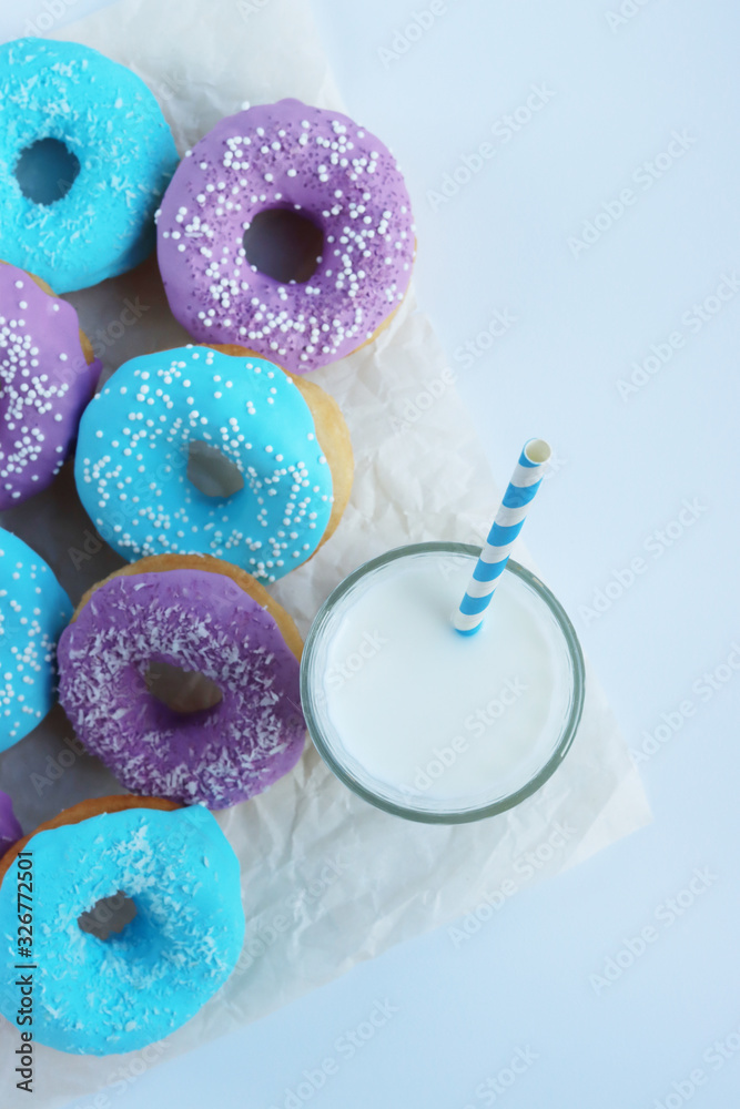 pink and blue doughnuts next to a glass of milk pink and blue doughnuts next to a glass of milk