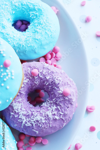 pink and blue doughnuts next to a glass of milk