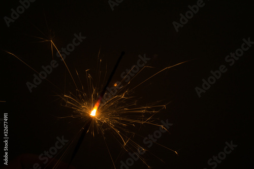 I hold a sparkler in my hand  which sparkles beautifully in different directions.