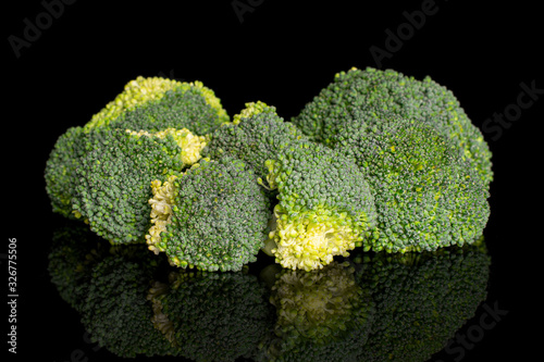 Group of six whole fresh green broccoli head isolated on black glass