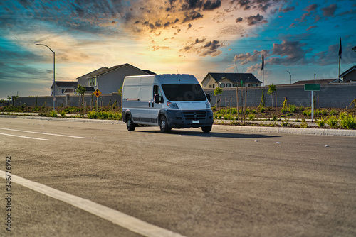 white cargo van driving down road during sunset photo