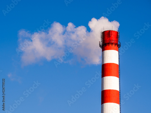 Heat and power central, smoke pipe against clear blue sky. The smoke from chimney of a power station. Smoking a pipe of heating plants supplying heat to the city. Smoking chimneys of the factory