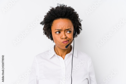 Young african american telemarketer woman isolated confused, feels doubtful and unsure.