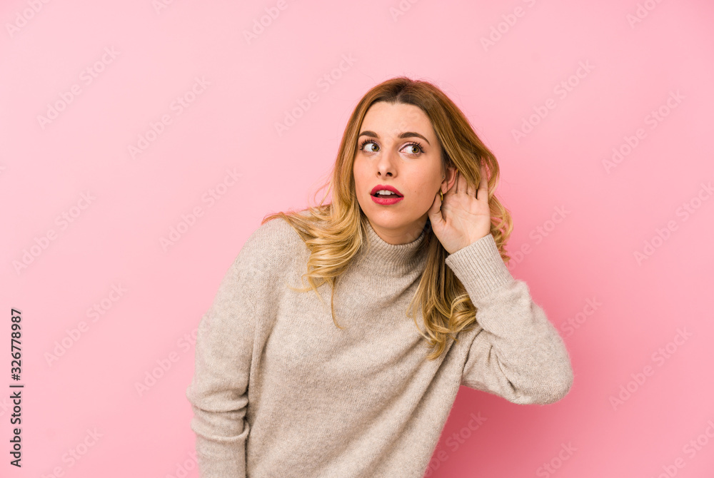 Young blonde cute woman wearing a sweater isolated trying to listening a gossip.