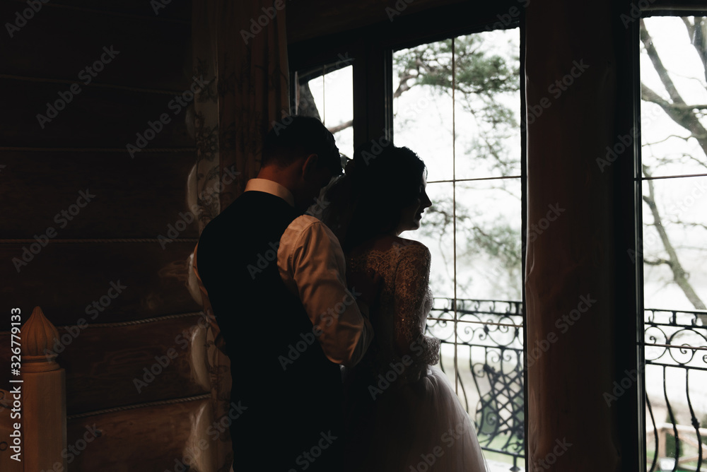 Morning of the wedding day. The bride and groom are standing at the window Morning of the wedding day. The bride and groom are standing at the window