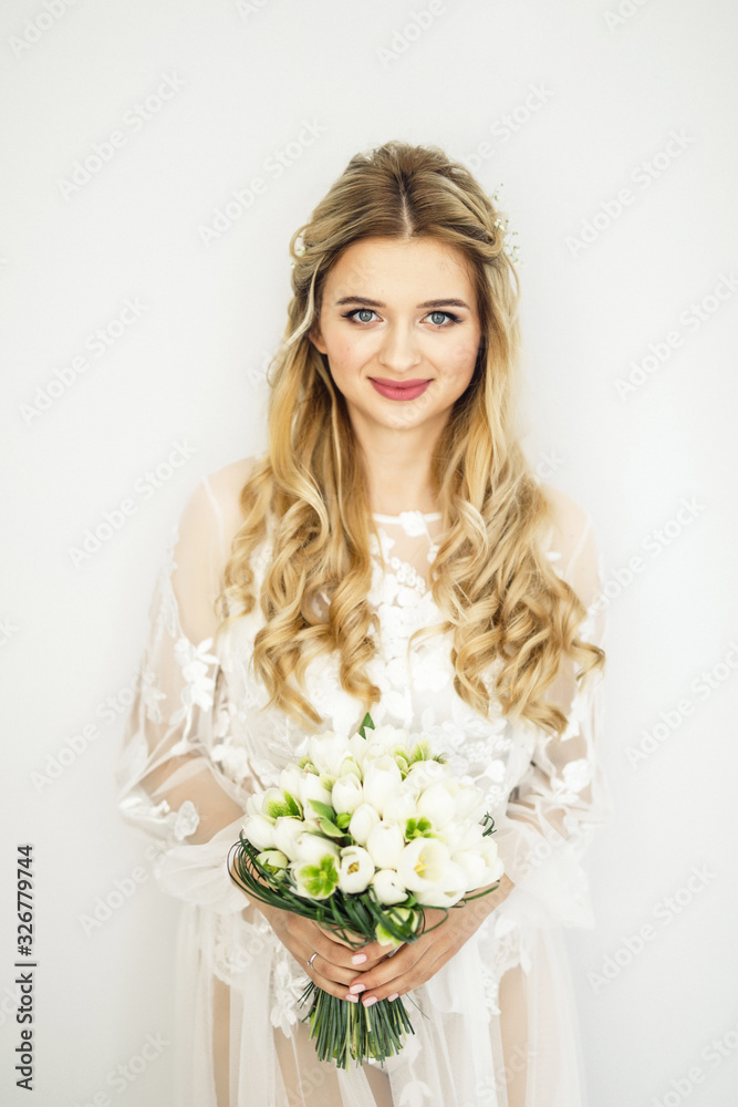 portrait of a young beautiful blonde bride with a bouquet in a white room portrait of a young beautiful blonde bride with a bouquet in a white room