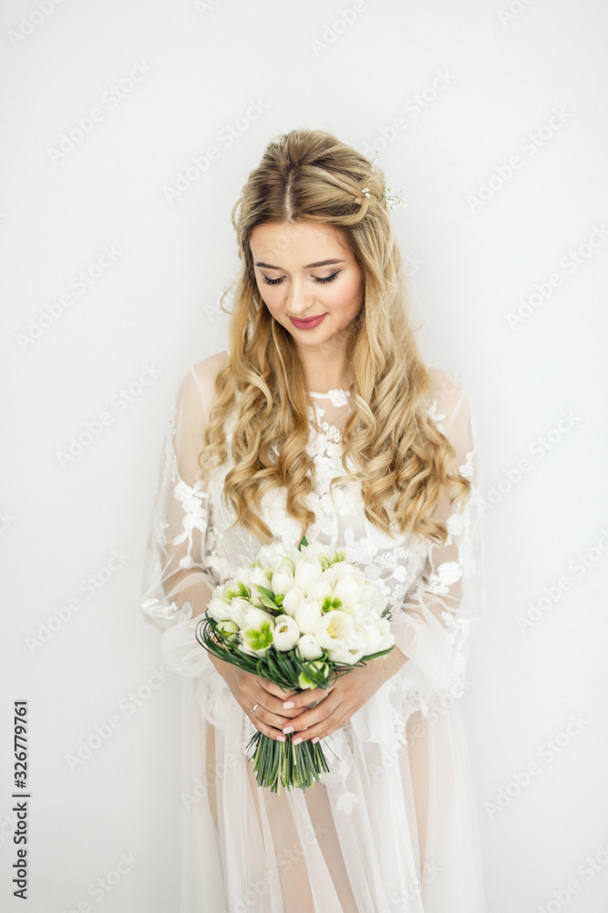 portrait of a young beautiful blonde bride with a bouquet in a white room portrait of a young beautiful blonde bride with a bouquet in a white room