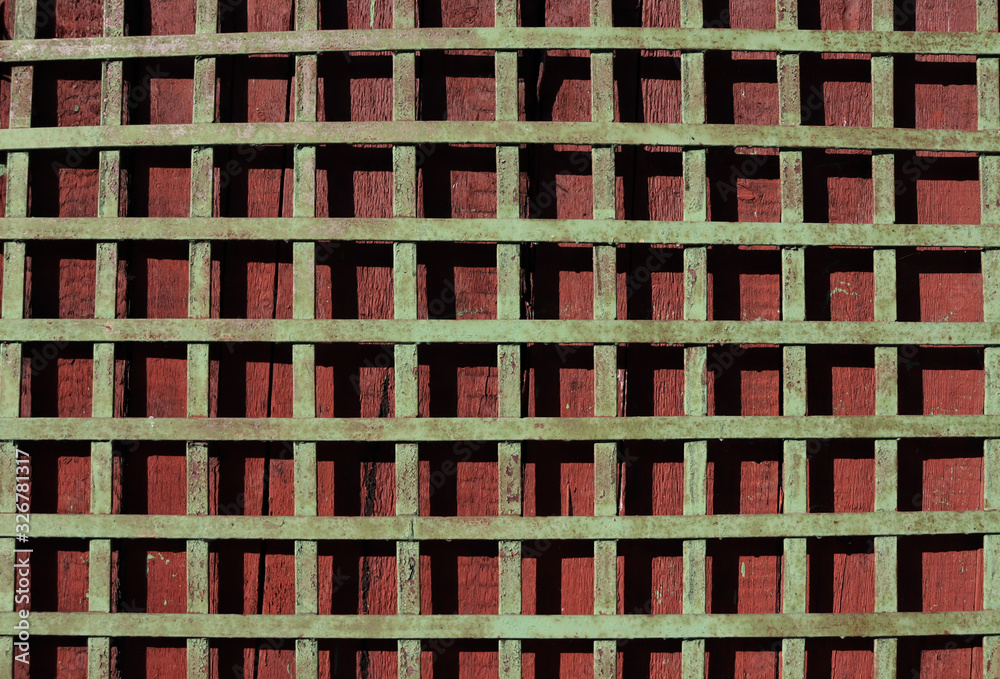 Iron mesh and wooden surface behind it. Background from a beautiful composition - a square lattice and mahogany behind it Iron mesh and wooden surface behind it. Background from a beautiful composition - a square lattice and mahogany behind it
