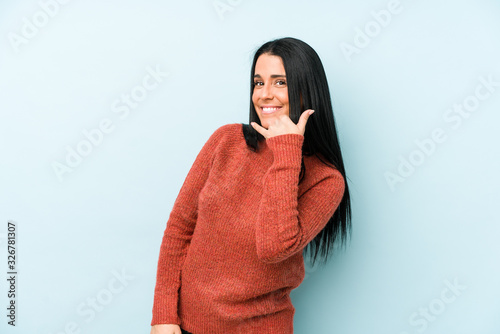 Young caucasian woman isolated on a blue background showing a mobile phone call gesture with fingers. © Asier