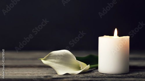 Burning candle and white calla lily on dark background with copy space. Sympathy card photo