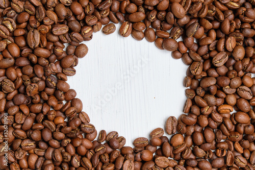 Coffee roasted grains on a white wooden background with a circle. Copy space.