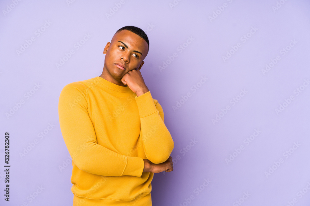 Young latin man isolated on purple background who feels sad and pensive, looking at copy space. Young latin man isolated on purple background who feels sad and pensive, looking at copy space.