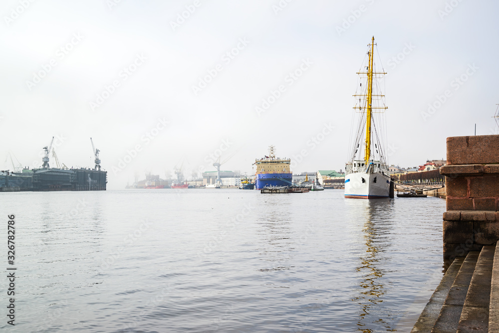 The embankment of the Neva with an icebreaker, a sailboat on a foggy spring warm day in April