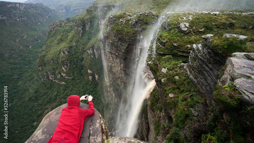 Traveler lies on the edge of the cliff and taking a picture of the waterfall in Chapada Diamantina national park, State of Bahia, Brazil. photo