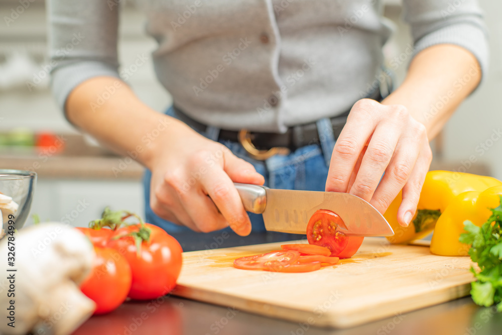 Woman is cutting tomatoes on cut board on kitchen. Woman is cutting tomatoes on cut board on kitchen.