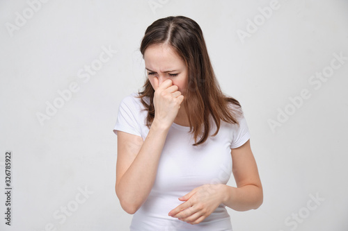 A girl in a white T-shirt has difficulty breathing through her nose. Consequences after plastic surgery.