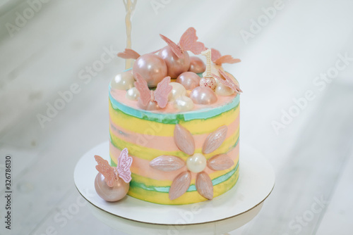 Decor of the girl's first birthday.  Beautiful delicate pink yellow cake with butterflies.