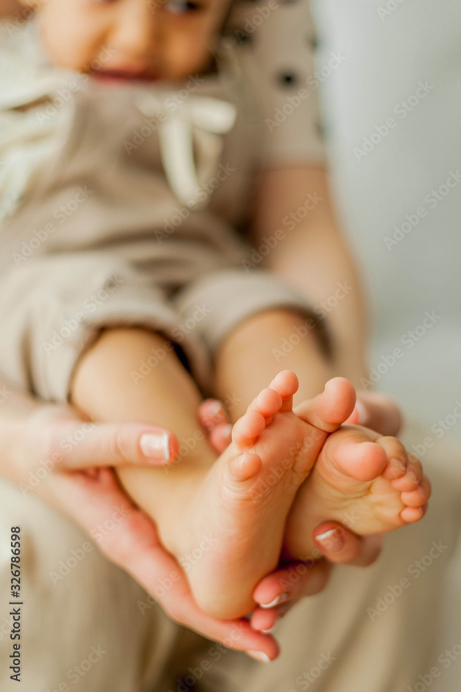 Close-up young mother holds in her hands the legs of the daughter of a Mothers Day. Close-up young mother holds in her hands the legs of the daughter of a Mothers Day.
