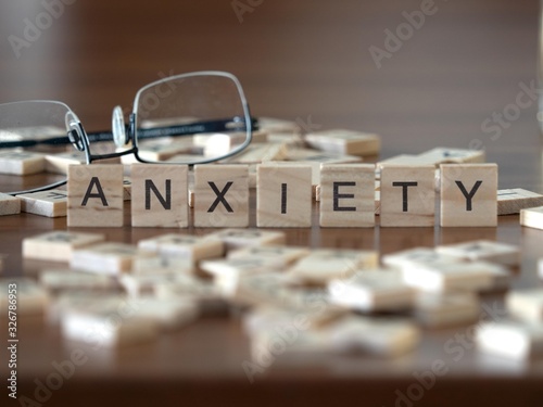 Photos anxiety concept represented by wooden letter tiles on a wooden table with glasse
