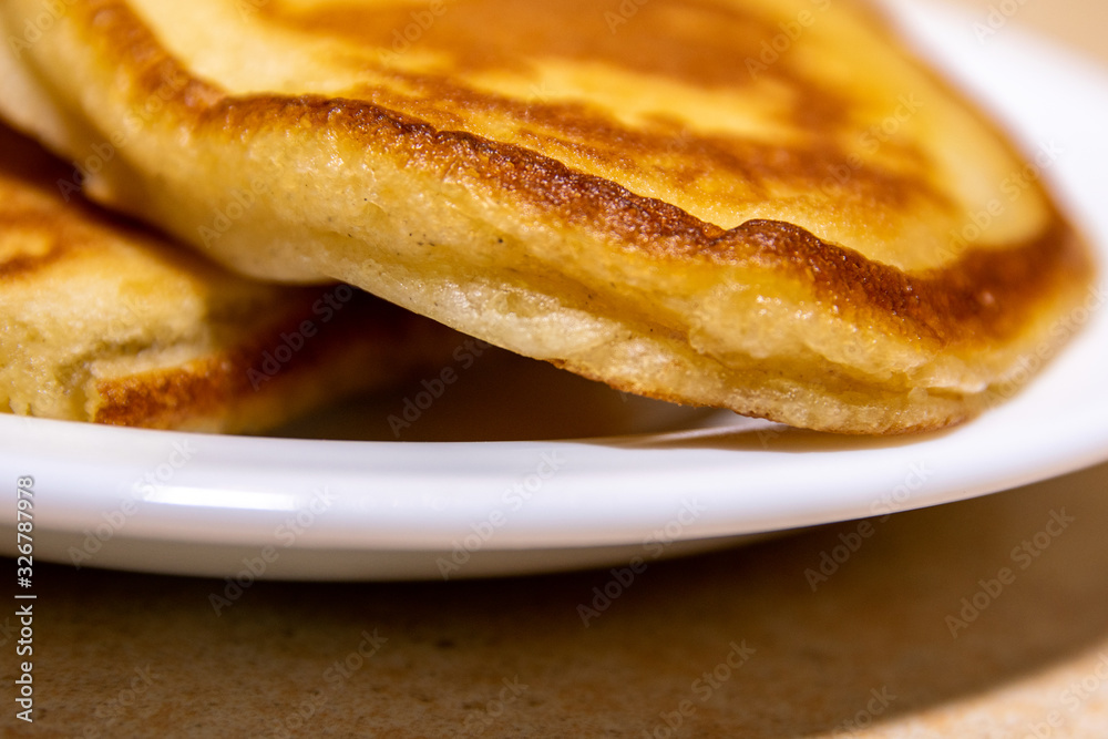 Baked thick brown pancakes on a white plate on the table. Baked thick brown pancakes on a white plate on the table.