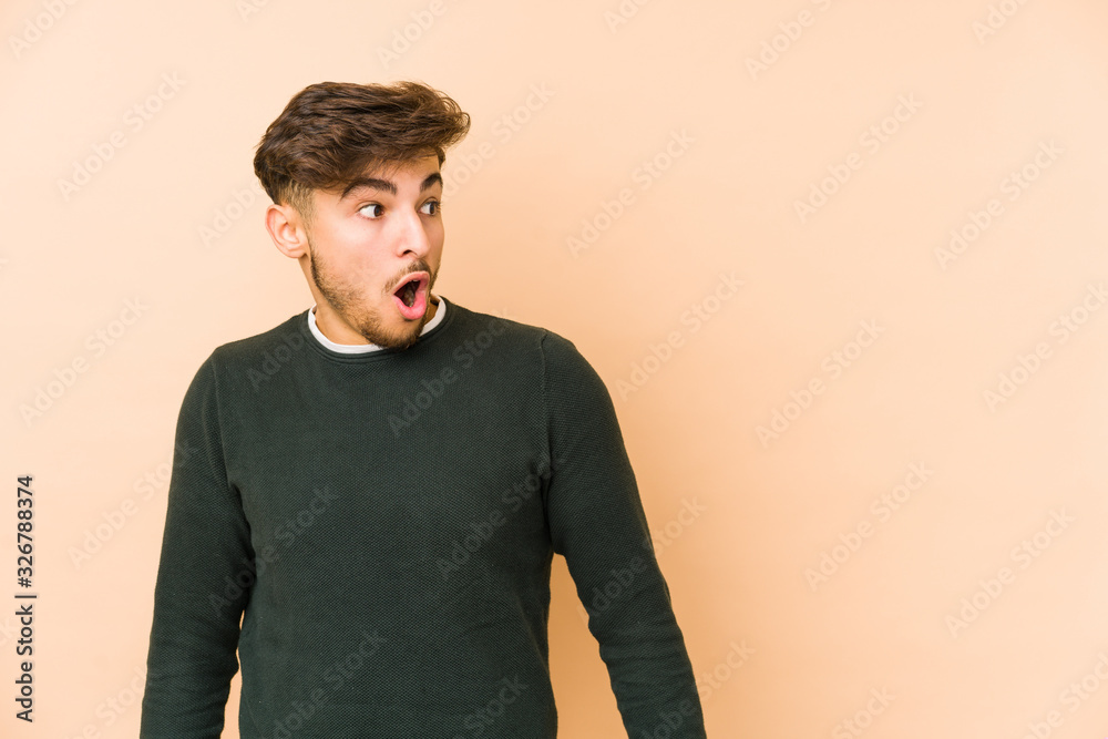 Young arabian man isolated on a beige background being shocked because of something she has seen. Young arabian man isolated on a beige background being shocked because of something she has seen.