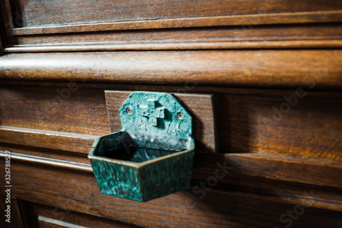 Defocused view of holy water recipient sanctified by a priest for the purpose of baptism, the blessing of persons, places, and objects, or as a means of repelling evil photo