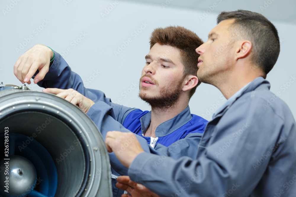 aero engineer and apprentice working on airplane in hangar aero engineer and apprentice working on airplane in hangar