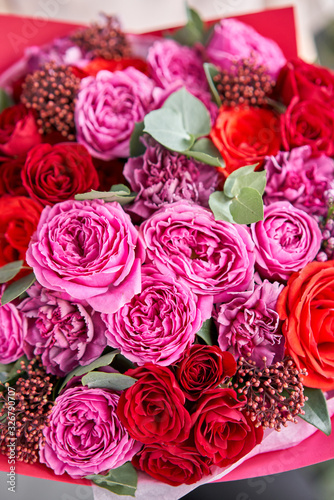 Closeup Bright berry color  Beautiful bouquet of mixed flowers in womans hands. the work of the florist at a flower shop. Delivery fresh cut flower. European floral shop.