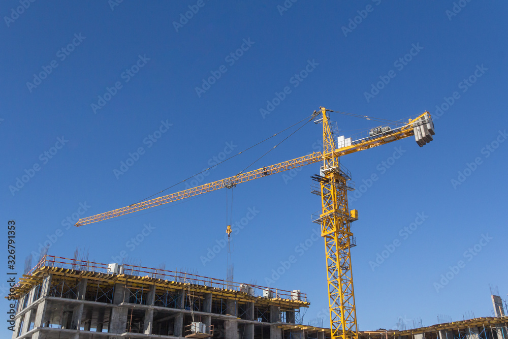 Construction crane on blue sky background. Lifting construction mechanism