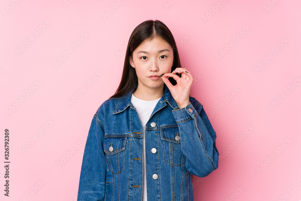 Young chinese woman posing in a pink background isolated with fingers on lips keeping a secret. Young chinese woman posing in a pink background isolated with fingers on lips keeping a secret.
