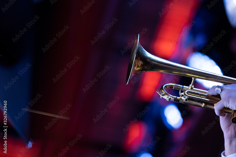 Obraz premium Główny trębacz w big bandzie grający solo w nastrojowym oświetleniu scenicznym
