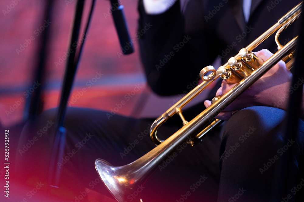 Obraz premium A trumpet player dressed in concert black sitting and holding a gold plated trumpet