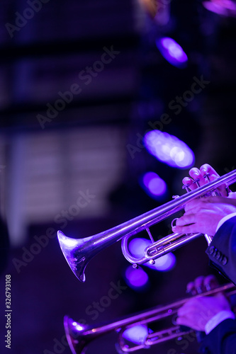  The trumpet section of a big band is playing a chorus during a concert on stage in purple stage lights